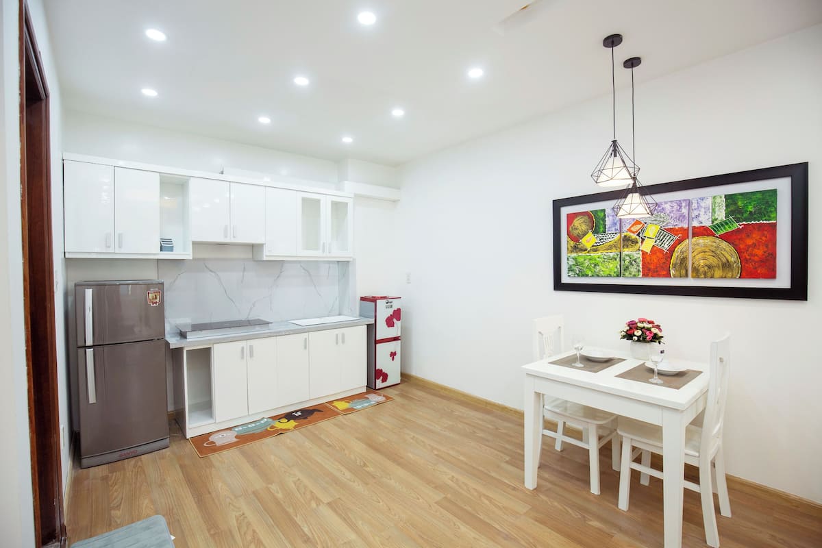 A modern kitchen with white cabinets, a refrigerator, and a dining table with chairs.