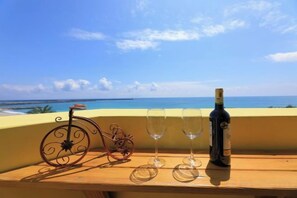 Una mesa con una botella de vino y dos copas, una bicicleta metálica decorativa y vistas al océano.