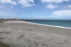 A beach with a cruise ship in the distance, a pier extending into the water, and a clear sky. - Nottingham Ocean Castle B&B (Hualien)