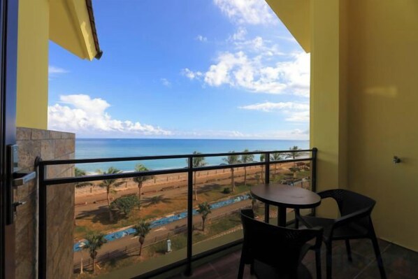 Un balcon avec vue sur l’océan et une table avec des chaises.