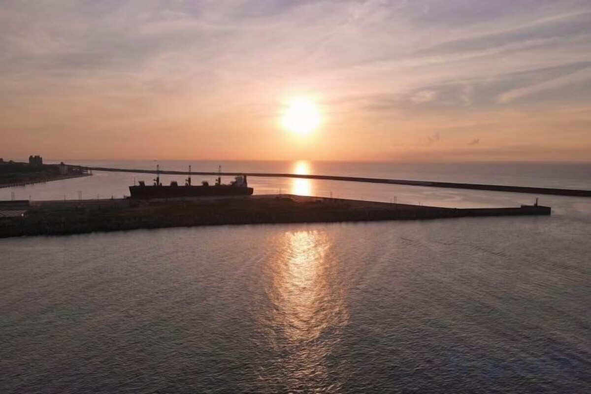 A sunset over a calm body of water with a pier extending into the water.