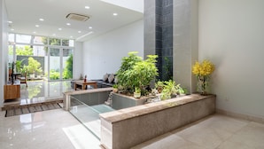A modern interior with a glass partition, a reception desk, and indoor plants. - Thao Dien Garden Villa 5BR Luxury Oasis By An Gia Hospitality (Ho Chi Minh City)