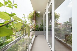 Ein Balkon mit Glasgeländer, Blumentöpfen und Blick auf die Stadt.