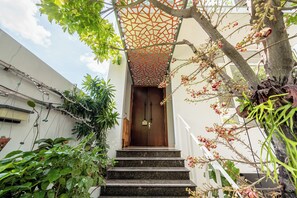 Eine Treppe führt zu einer Holztür mit einer verzierten Überkonstruktion.