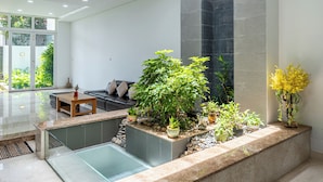 A modern interior with a glass pool, seating area, and potted plants. - Thao Dien Garden Villa 5BR Luxury Oasis By An Gia Hospitality (Ho Chi Minh City)