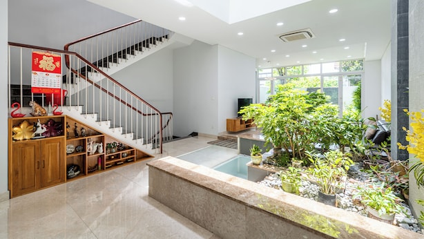 A spacious indoor area with a staircase, a small indoor garden, and a seating area with a television. - Thao Dien Garden Villa 5BR Luxury Oasis By An Gia Hospitality (Ho Chi Minh City)