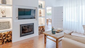 A modern living room with a fireplace, a TV mounted on the wall, and a dining area with a table and chairs. - Cofitsa Plus by Interhome (Jávea)