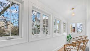 A bright room with large windows, a wicker chair, and a small plant. - Old-Portland Charmer in the Alphabet District (Portland)