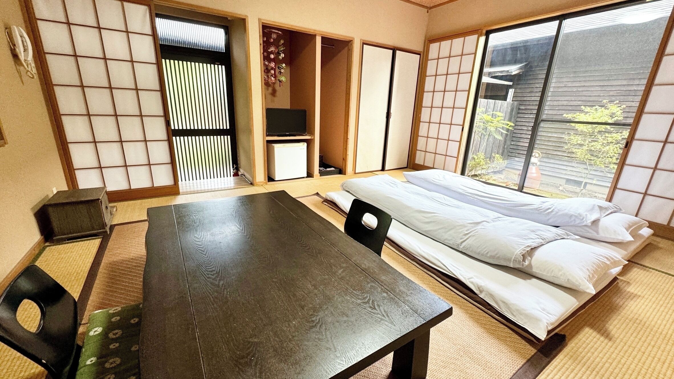 Um quarto japonês tradicional com tatames, futon, mesa baixa e portas deslizantes.