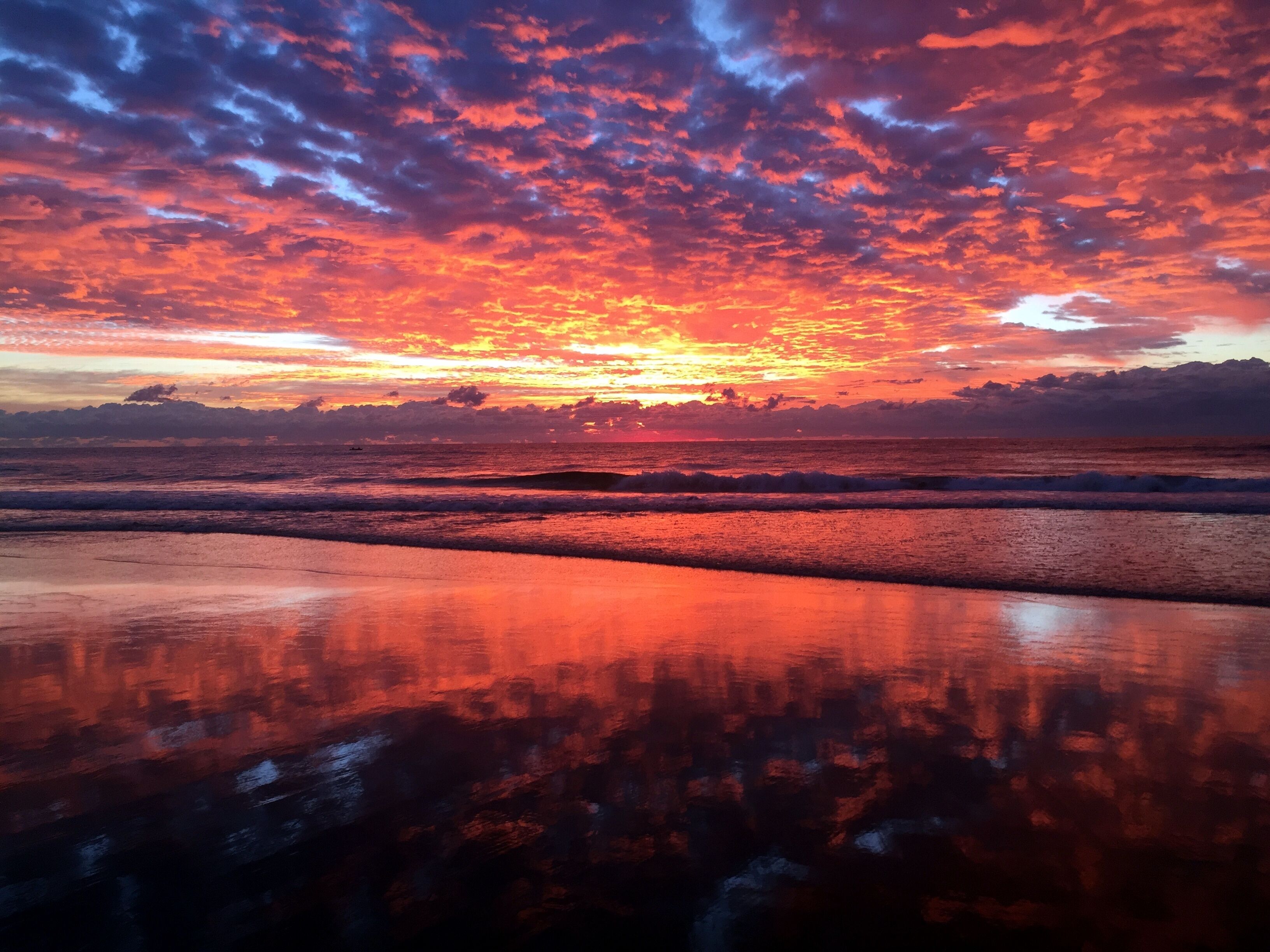 A beach with a sunset and ocean waves.