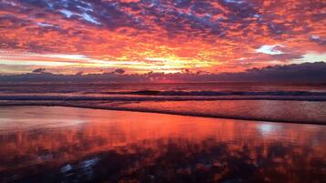 A beach with a sunset and ocean waves.
