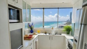 Een moderne keuken met uitzicht op zee en stadshemel, voorzien van een magnetron, oven en spoelbak.