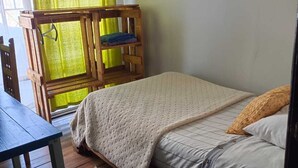 Ein gemütliches Zimmer mit einem hölzernen Bett, einem kleinen Holztisch und einem farbenfrohen Teppich.