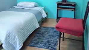 Ein kleines, ordentliches Zimmer mit einem Bett, einem Schreibtisch und einem Stuhl.