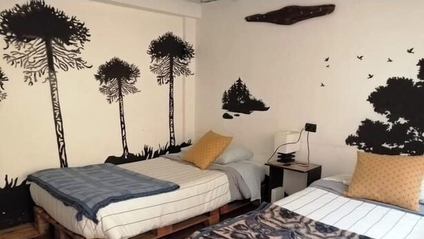 Ein Schlafzimmer mit zwei Betten, einem Nachttisch und Wandbildern.