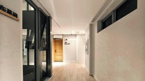 Un pasillo con suelo de madera, una puerta al final y un cartel en la pared.