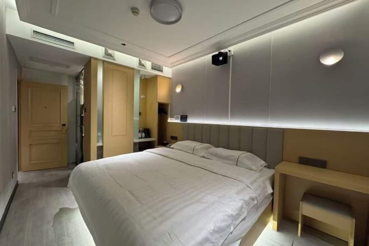 A hotel room with a large bed, a bedside table, a wardrobe, and a mirror.