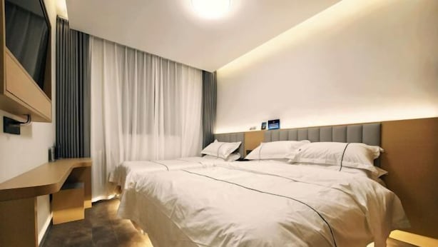 Una habitación de hotel con una cama grande, un escritorio y un televisor montado en la pared.