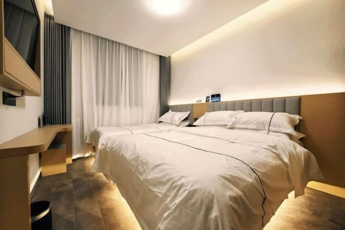 A hotel room with a large bed, a desk, and a TV mounted on the wall.