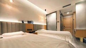 Habitación de hotel con dos camas, una mesita de noche, un armario y la puerta del baño.