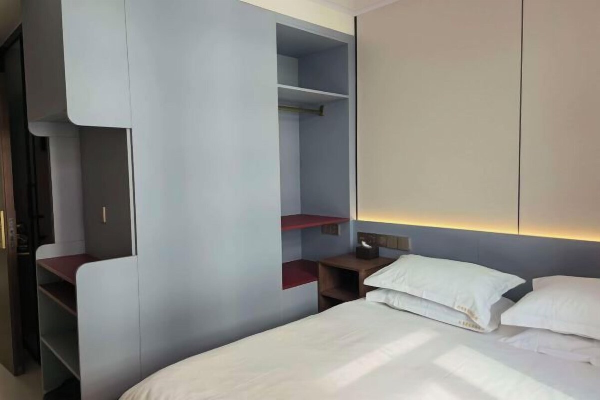 Una habitación de hotel moderna con una cama, un armario y una mesita de noche.
