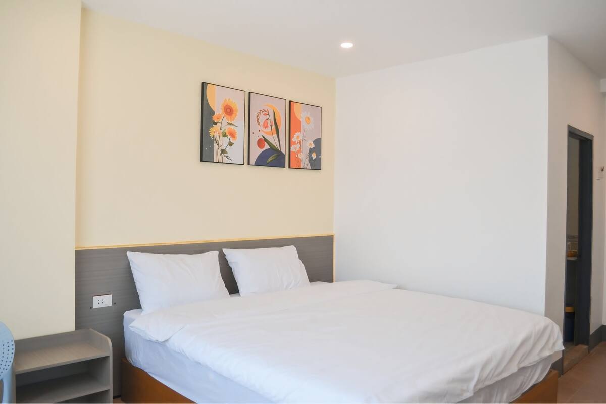 A hotel room with a large bed, a bedside table, and a wall-mounted artwork.