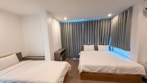 A hotel room with two single beds, a small desk, and a large window with curtains. - Apollo Vientiane Hotel (Vientiane)