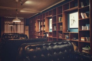 Una sala de estar acogedora con un sofá de cuero, un televisor y una estantería.