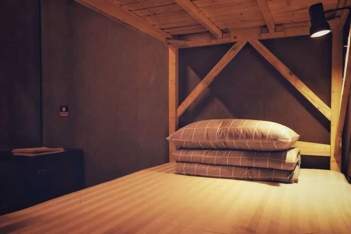 Un lit simple avec une tête de lit en bois, une table de chevet et une lampe.