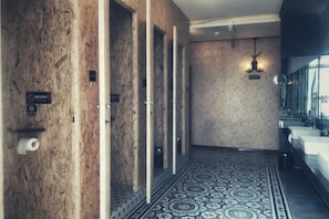 A hotel hallway with multiple doors, a patterned floor, and a mirror on the right wall. - up north hostel (Dunhuang)