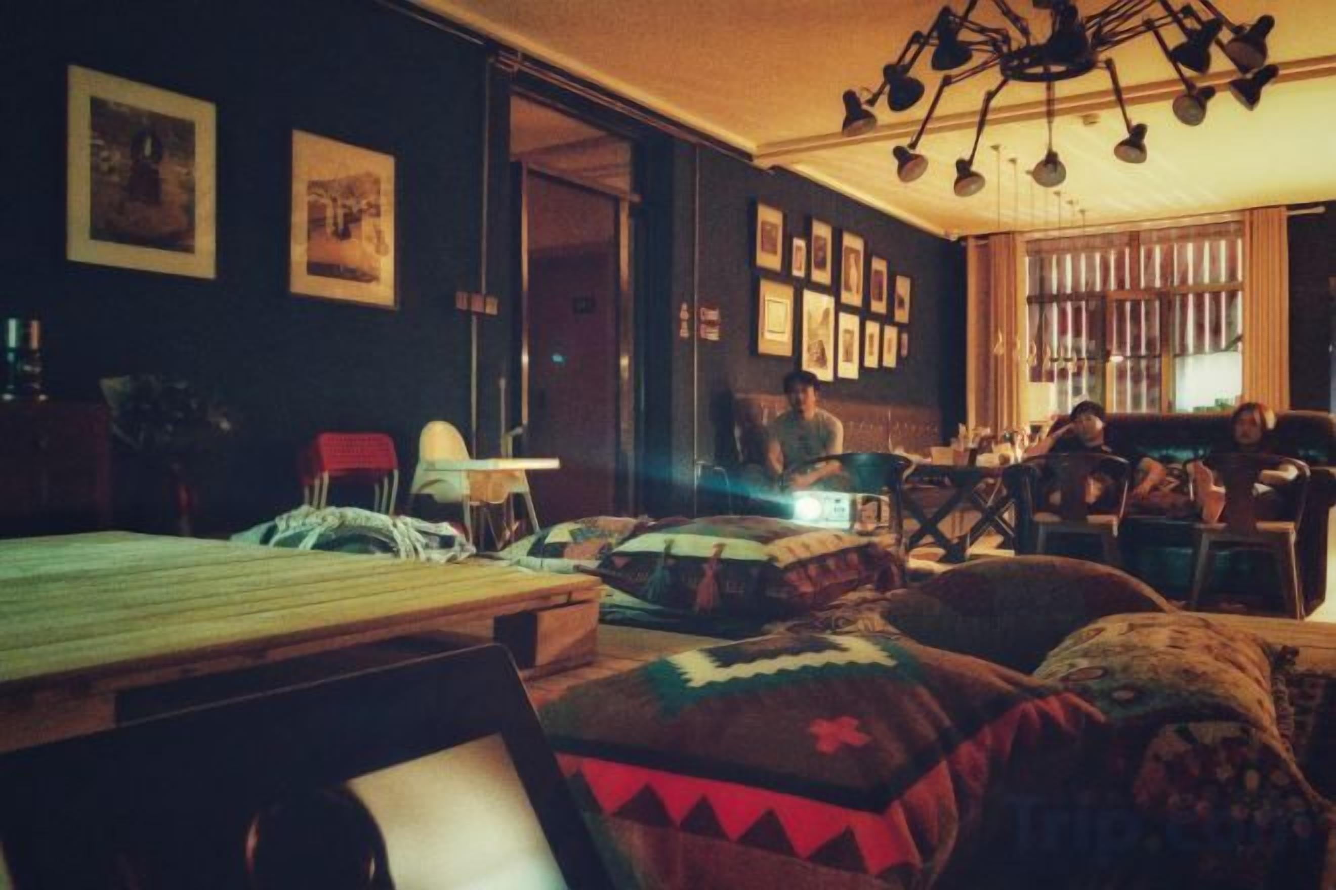 A room with a bed, a desk, and a chair. There are pictures on the wall and a window with blinds.
