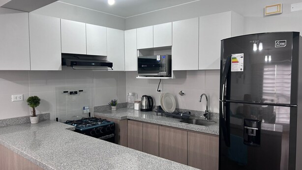 A modern kitchen with white cabinets, a stainless steel refrigerator, a gas stove, and a microwave.