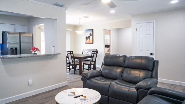 A modern living room with a leather sofa, a round coffee table, and a dining area with a table and chairs.