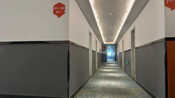 Ein langer, schmaler Hotelgang mit Hinweisschildern an den Wänden.