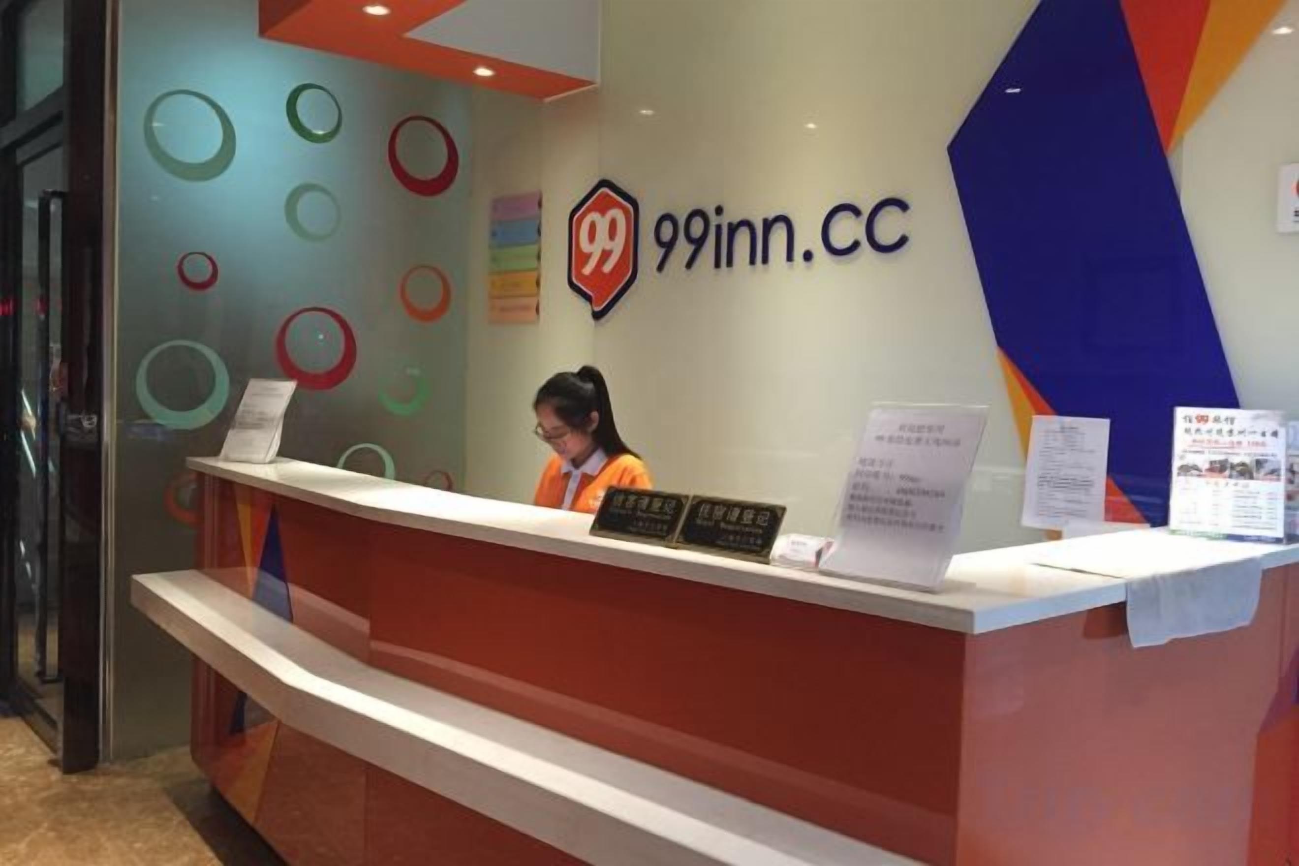 A reception desk with a sign reading '99inn.CC' and a receptionist behind it.