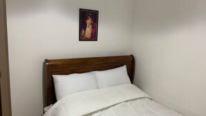 A single bed with a wooden headboard in a room with plain white walls. - Room-king Bed With Shared Bath (Dublin)