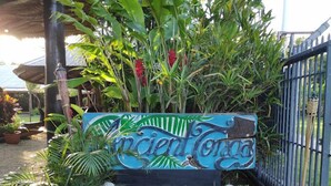 Un letrero con la inscripción 'Ancient Tonga' rodeado de vegetación exuberante y una valla metálica.