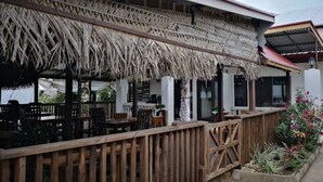 Un restaurante con techo de paja y mobiliario de madera.