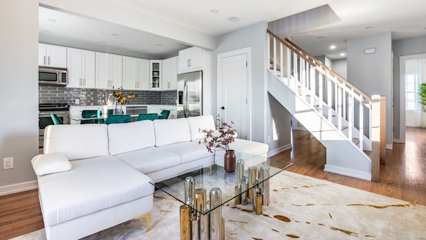 A modern living room with a glass coffee table, white sofa, and a staircase leading to an upper level. - 3BR Prime Luxury near NYC w Arcade Room (Yonkers)