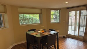 A dining area with a table set for four, surrounded by chairs, with a window providing a view of greenery outside. - Charming 2 bedroom bed & breakfast in fabulous Niagara-on-the-Lake with pool (Niagara-on-the-Lake)