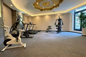 A gym with stationary bikes, treadmills, and a rowing machine. - Shangdong Lake Hotel (Kuytun)