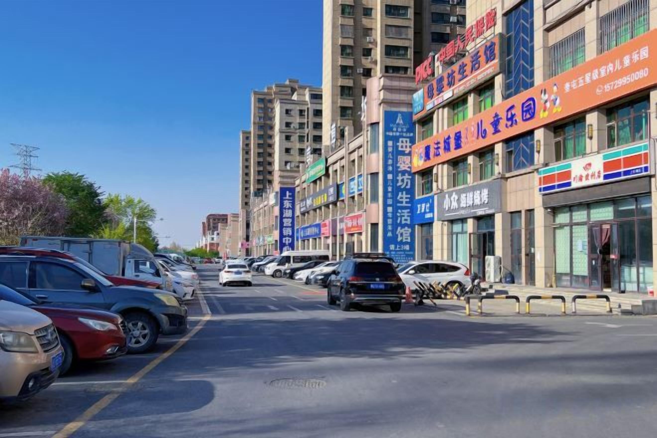 A street with parked cars and buildings with commercial signs.