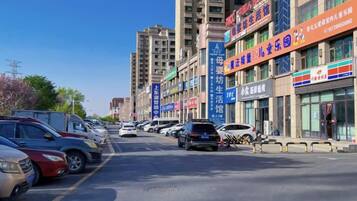 A street with parked cars and buildings with commercial signs.