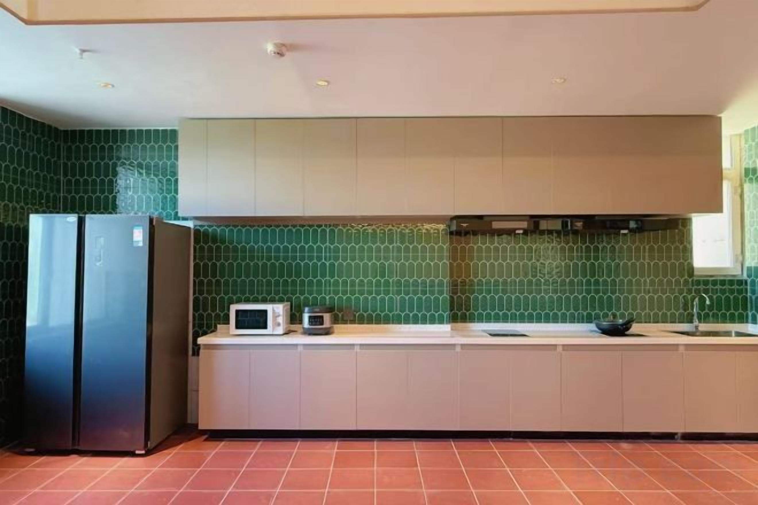 A kitchen with a refrigerator, microwave, and a sink.