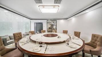 A modern conference room with a round table, beige chairs, and a glass partition.
