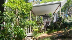 A modern house with a covered outdoor area, a staircase, and lush greenery. - Private, Secluded Retreat - Our Reviews Say it All (Smiths Lake)