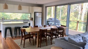 A modern kitchen with a dining area, large windows, and a view of the outdoors. - Private, Secluded Retreat - Our Reviews Say it All (Smiths Lake)