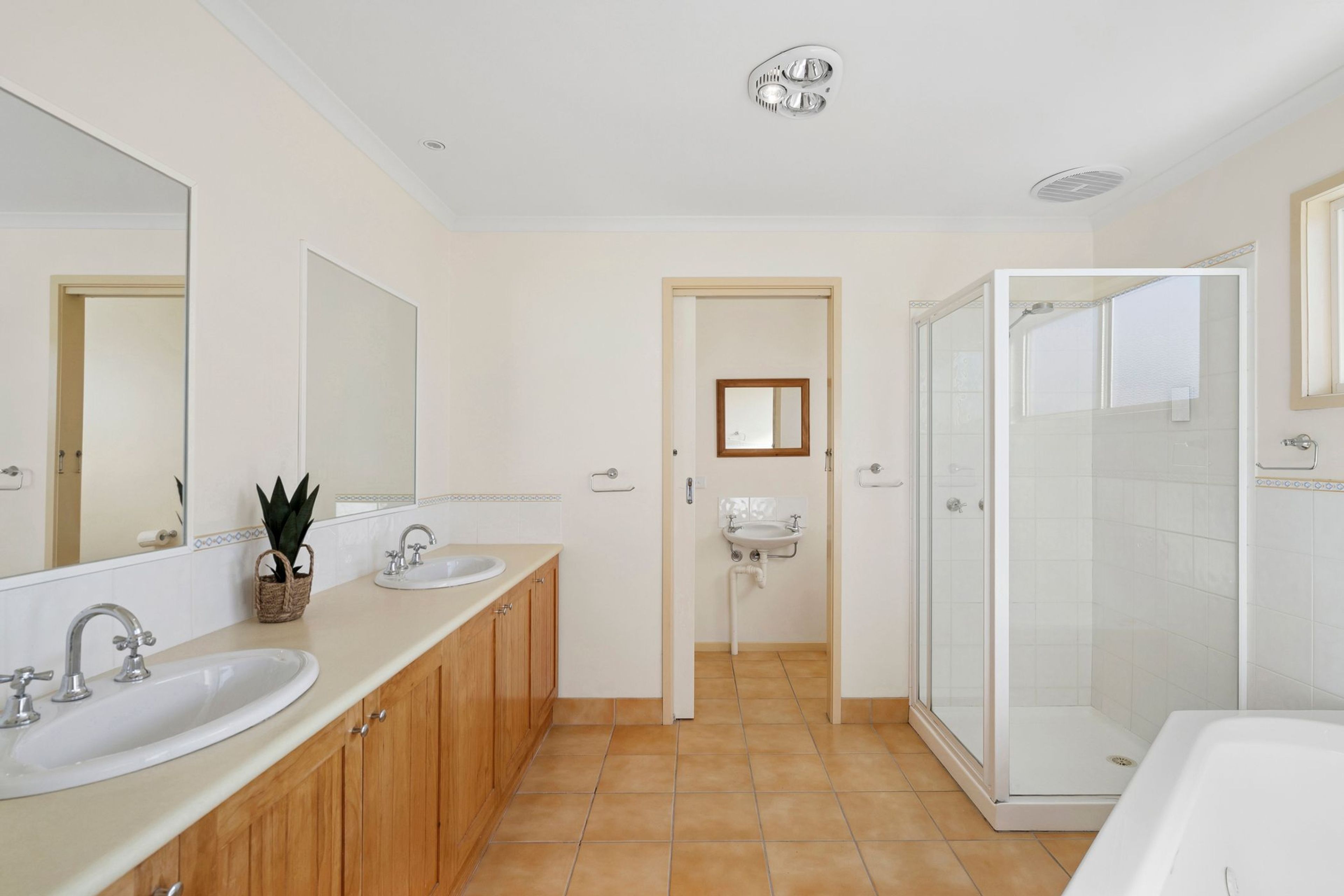 A modern bathroom with two sinks, a shower, and a mirror.