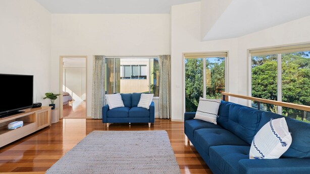 A spacious living room with a large flat-screen TV, a blue sofa, and a matching armchair. - Family Tides (Apollo Bay)