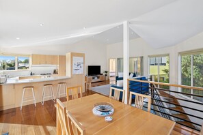 Een modern interieur met een eethoek, keuken, woonruimte en een trap naar een hoger gelegen verdieping.